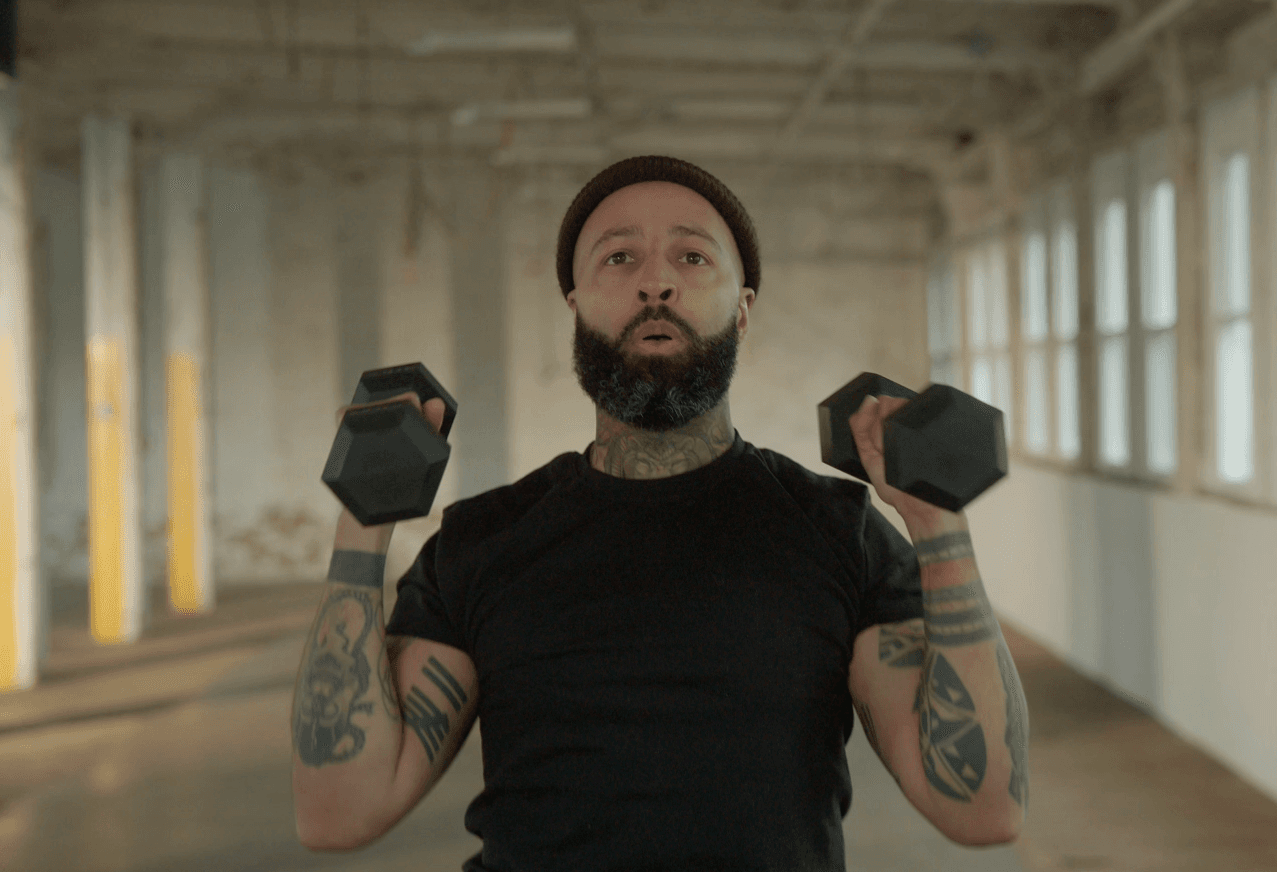 Man performing a seated dumbbell shoulder press during a guided workout