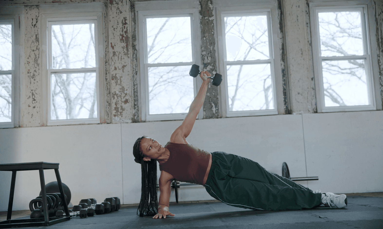 Woman performing a side plank and dumbbell reach during a strength workout