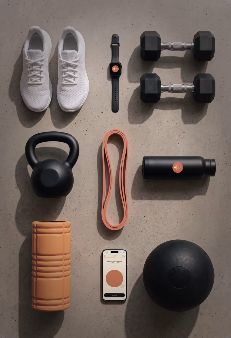 Sneakers, dumbbells, a kettlebell, resistance bands and a foam roller laid out on the floor