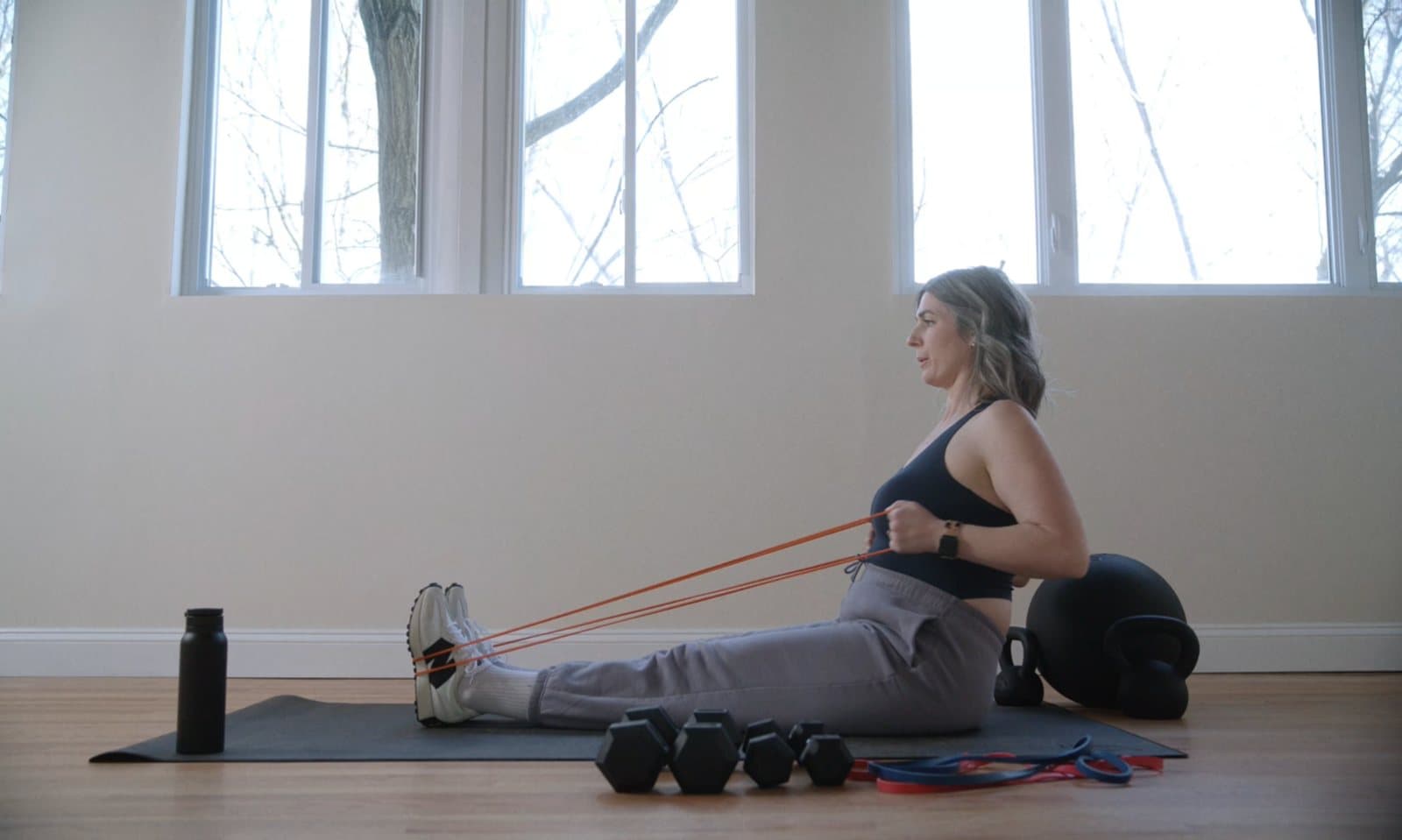 Woman over 40 doing a seated resistance band strength workout at home