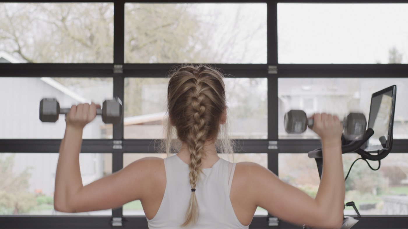 Person doing dumbbell shoulder presses during a home strength workout